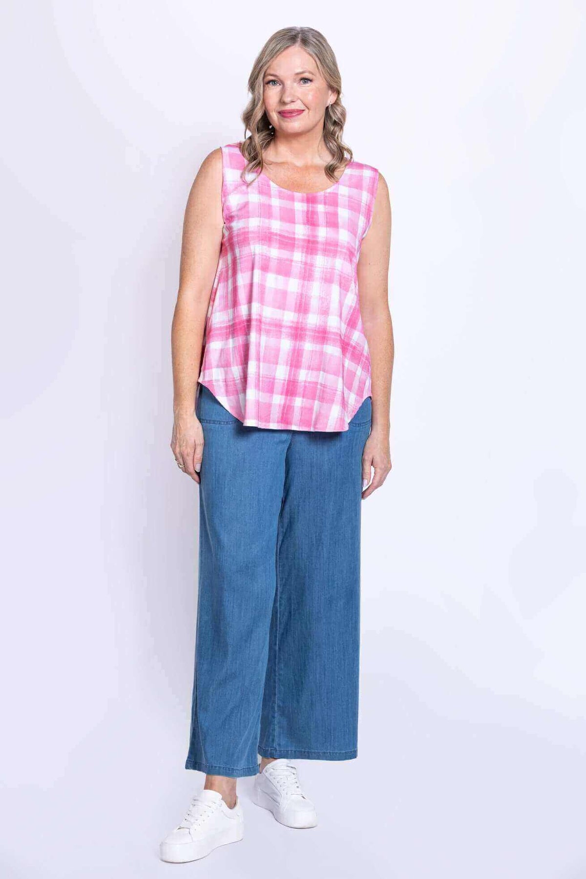 Full front view of woman in pink plaid sleeveless tank with relaxed blue jeans