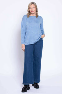 Front facing woman in wide leg medium wash jeans and relaxed blue sweater