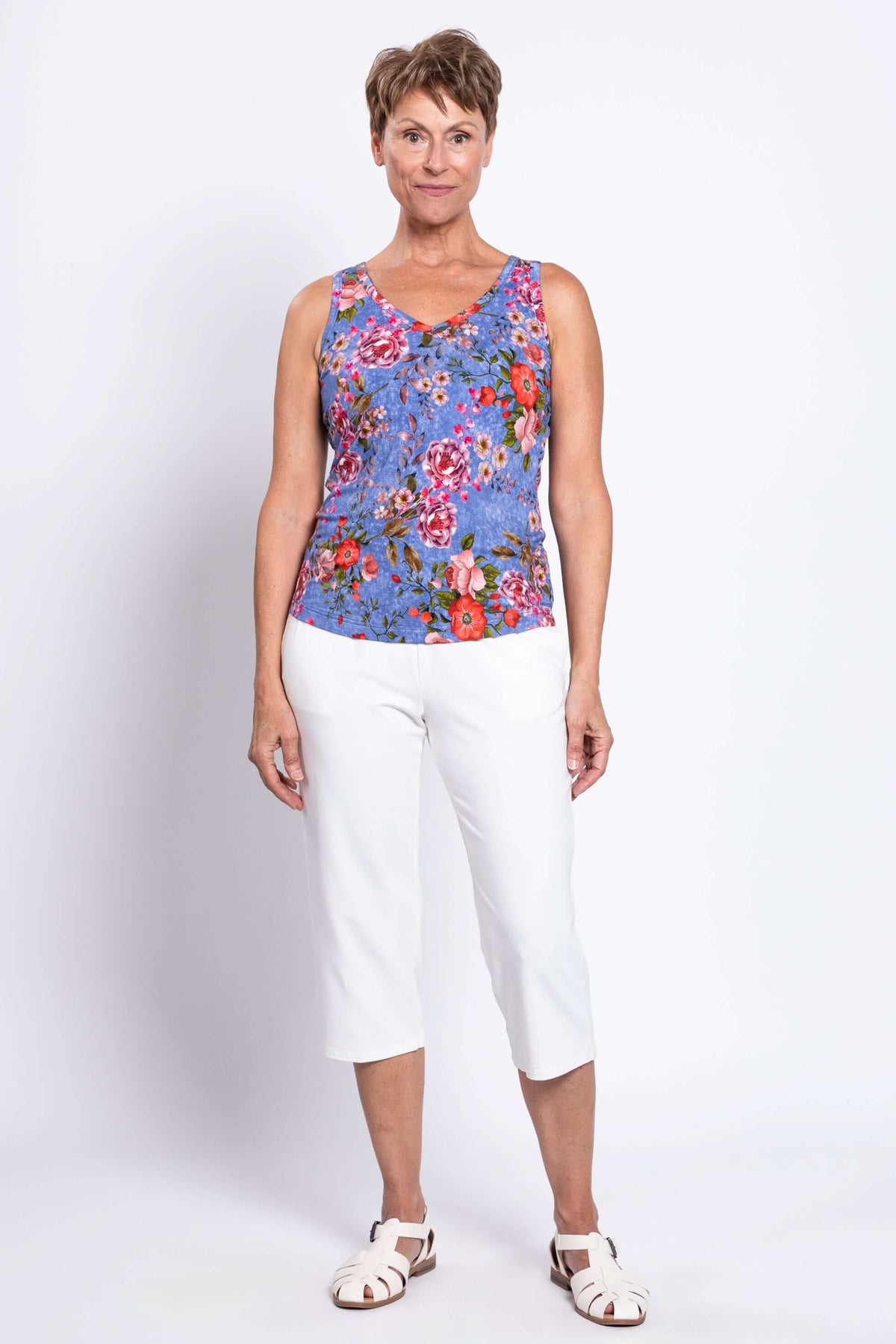 Full body front view of woman in blue floral bamboo tank and white cropped pants