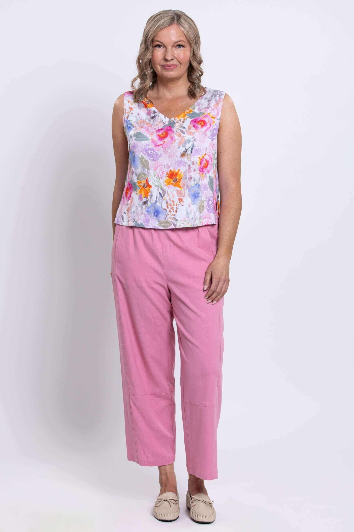Full front view of woman in floral cropped tank and pink trousers