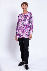 Full body front view of woman in floral tunic top with black pants