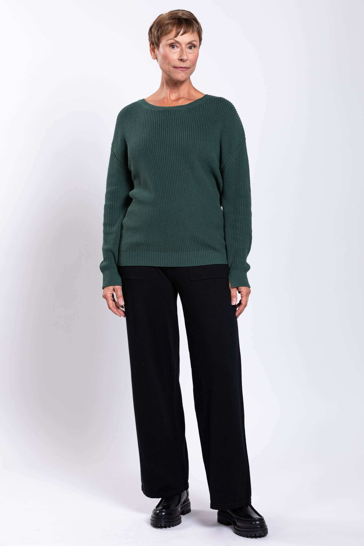Full front view of woman in green sweater and black wide-leg pants