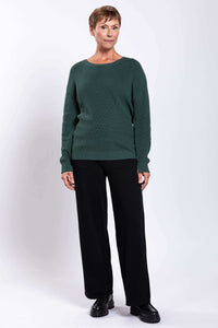 Full front view of woman in green sweater and black wide-leg pants