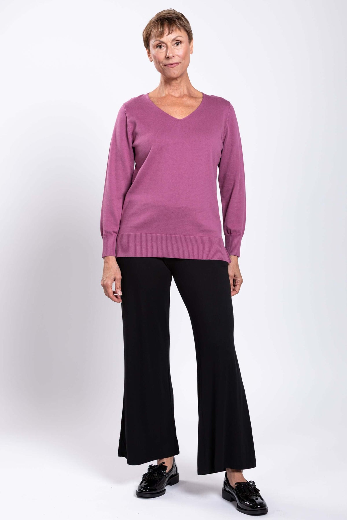 Full front view of woman in mauve V-neck sweater and black pants