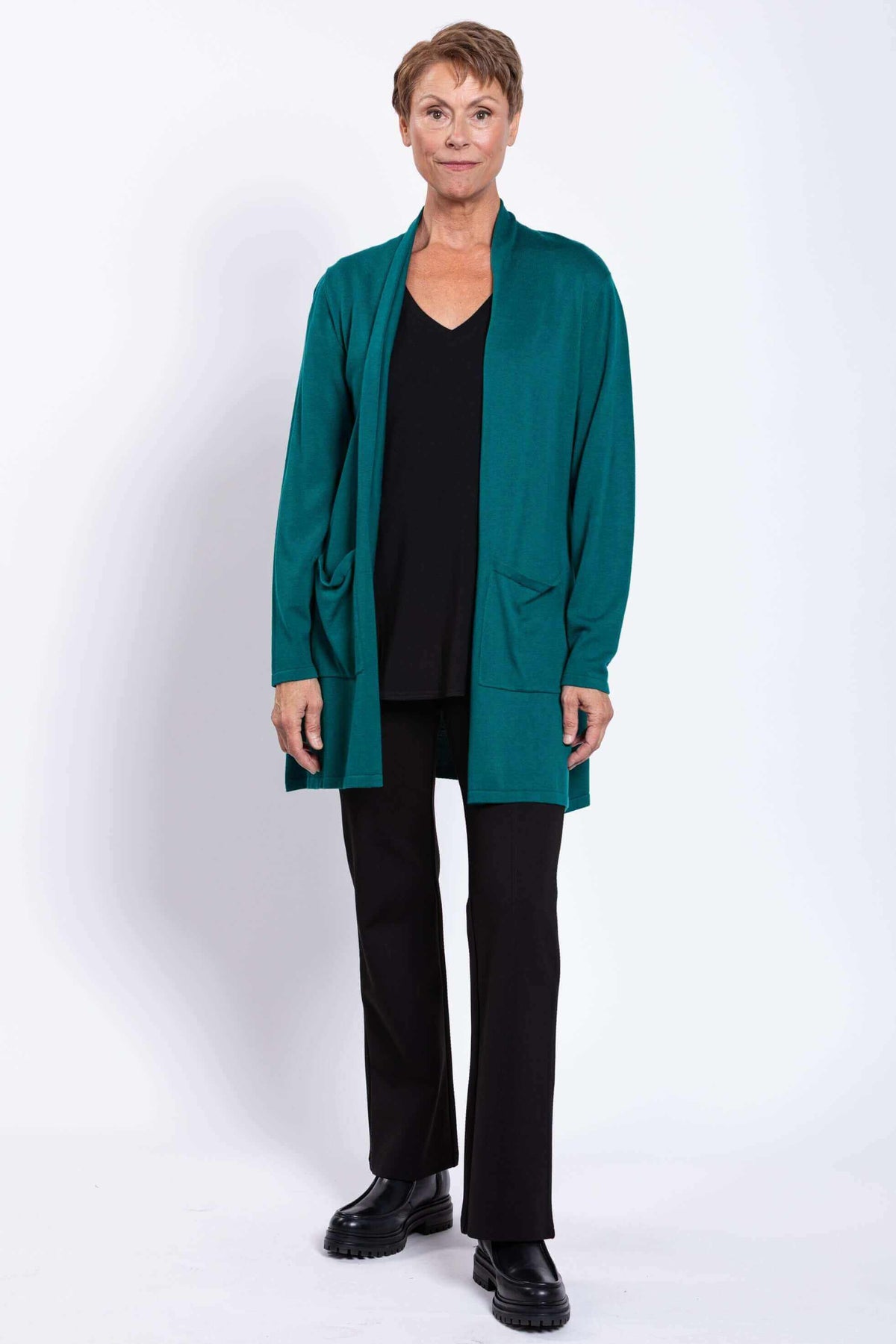 Full front view of woman in teal cardigan, black pants, and black shoes