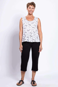 Full front view of woman in white floral peplum tank and black pants