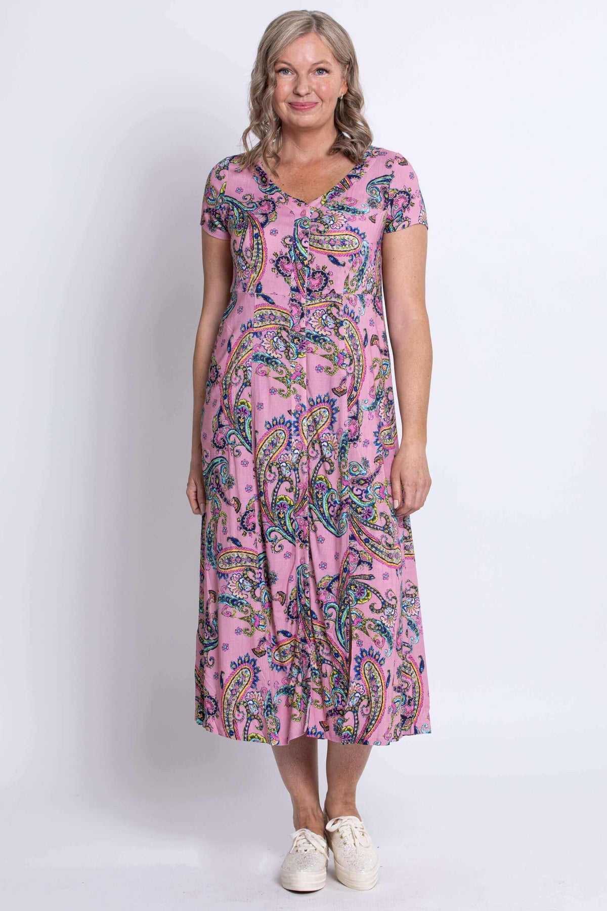 Full front view of woman wearing pink paisley midi dress and white sneakers