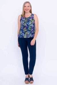 Full body front view of woman in colorful fern print tank and navy pants