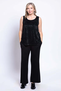 Full front view of a woman in a sleeveless black lace top and black pants