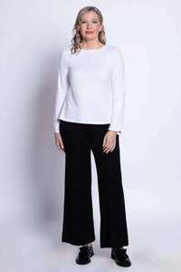 Full front view of woman in white long sleeve top and black wide leg pants