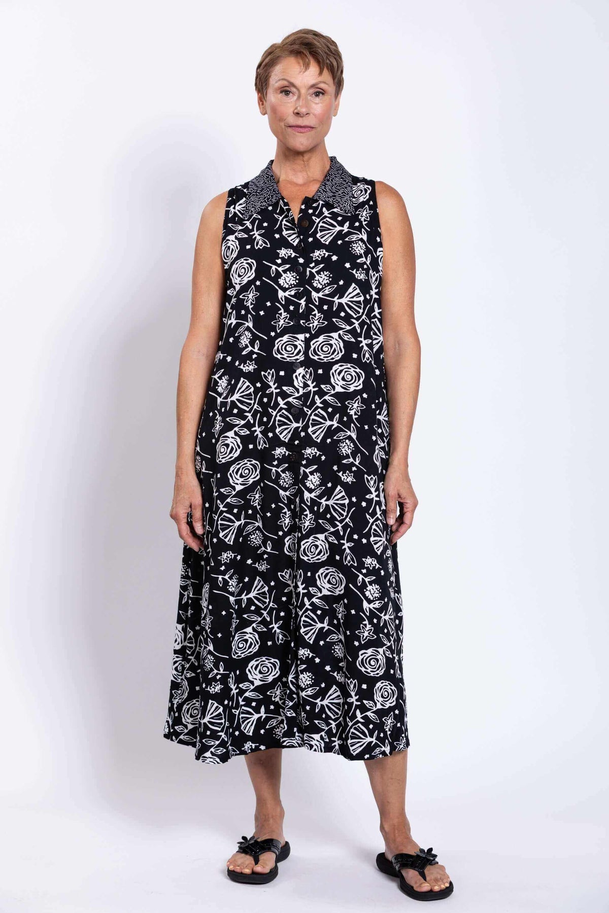Full frontal view of woman in black A-line dress with white floral graphics