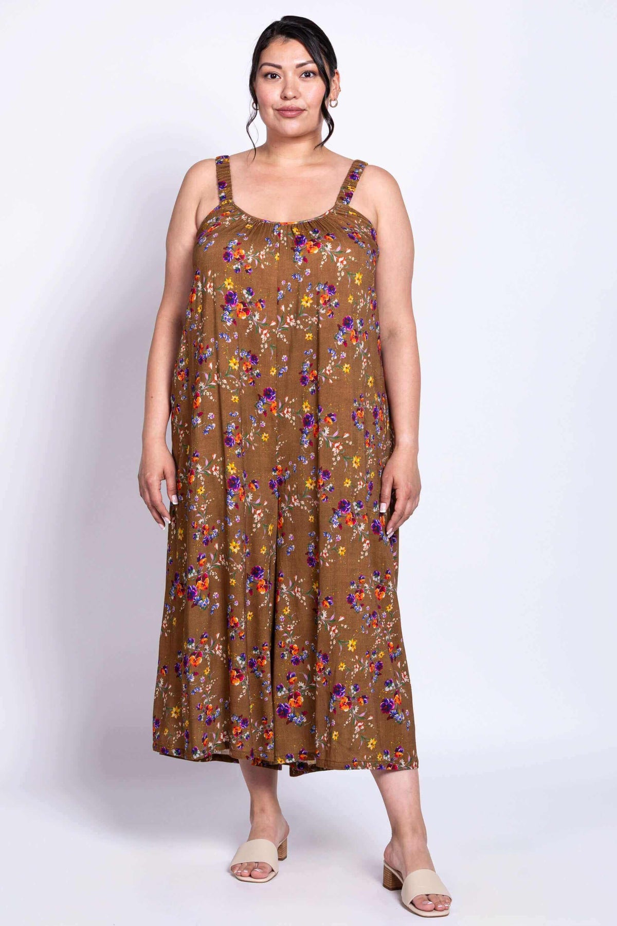 Person wearing a brown floral jumpsuit, standing straight, full front view