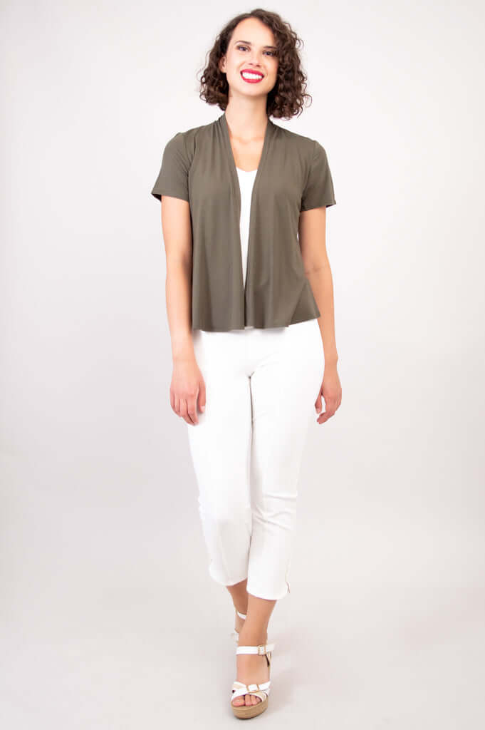 Woman standing in olive green bamboo layering jacket and white crop pants