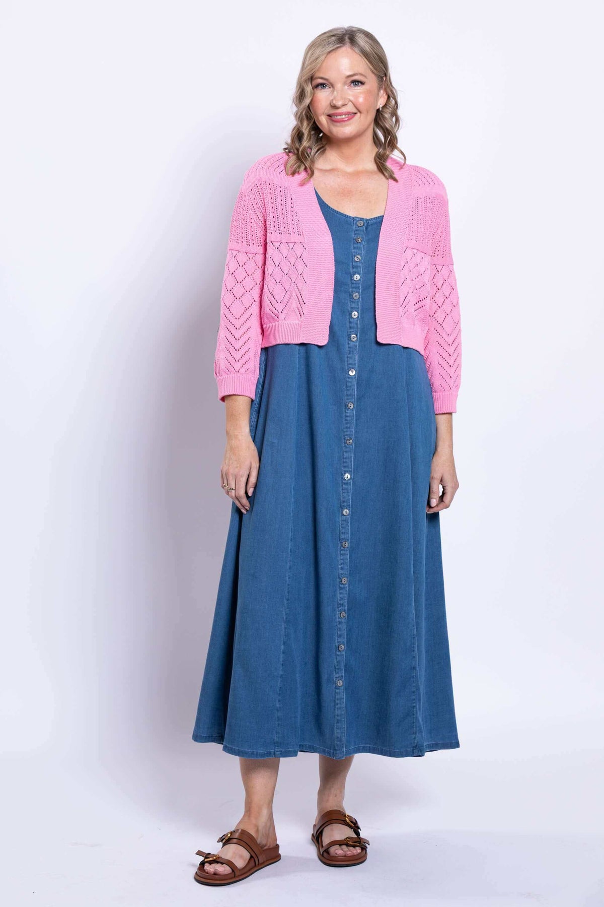 Full body view of model in pink cropped cardigan and blue button-front dress
