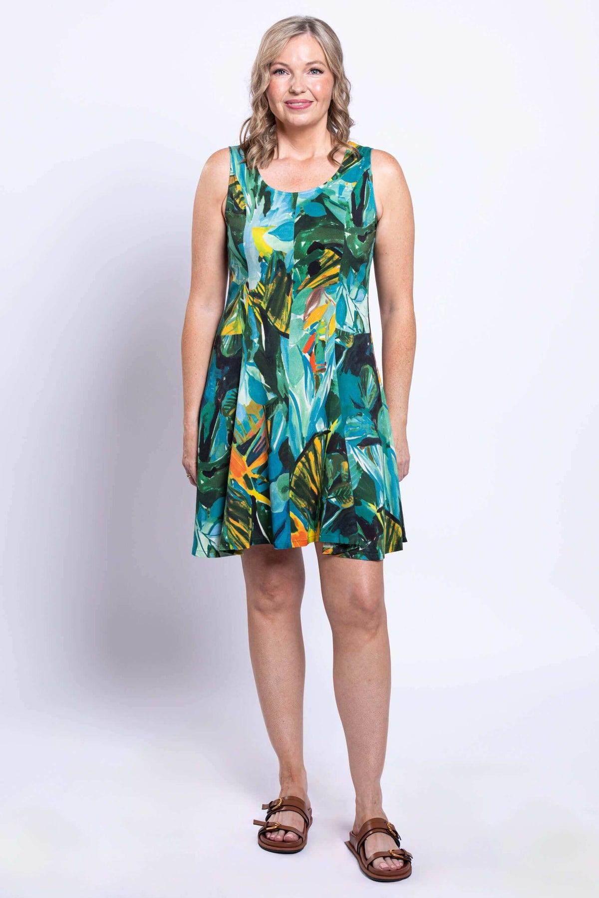 Full view of woman standing in knee-length rainforest print dress, facing forward