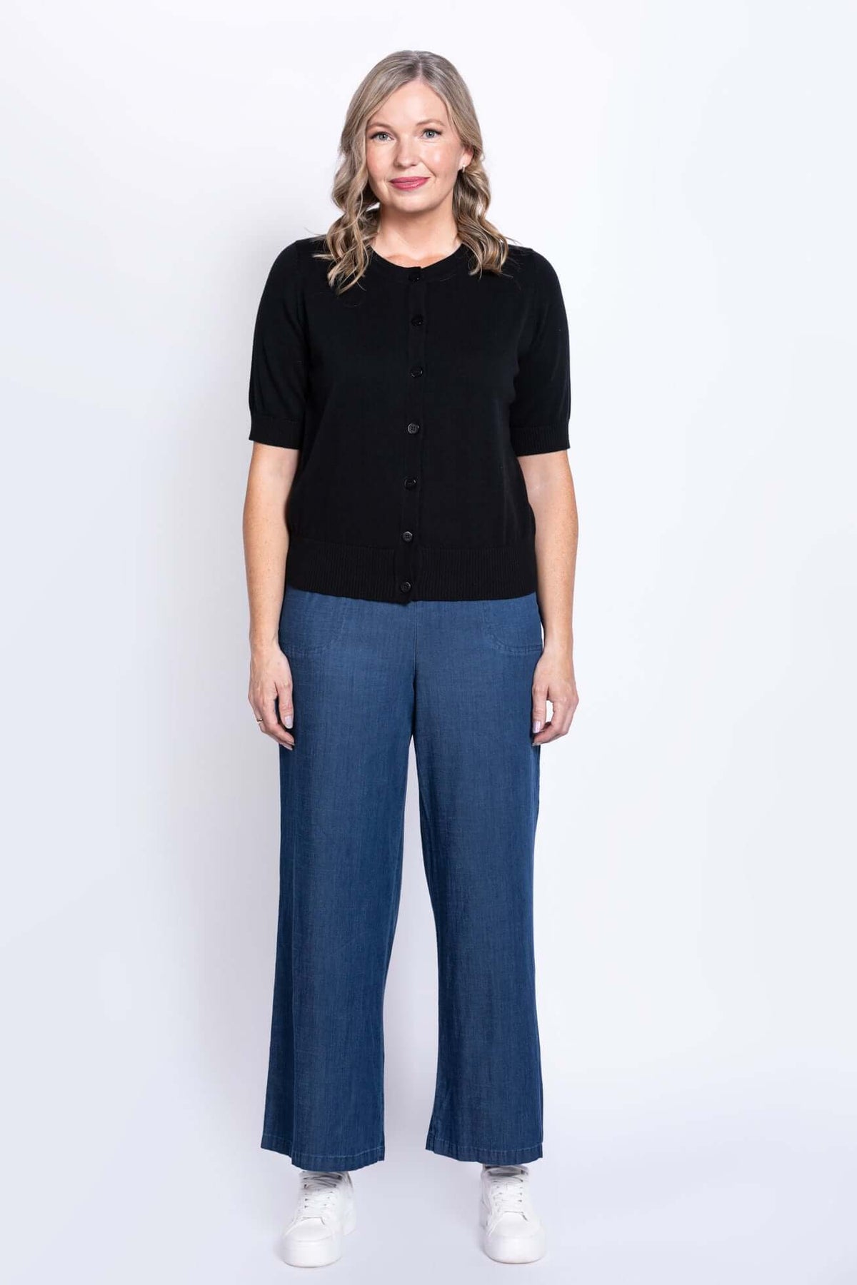 Full length front view of woman in black cardigan and blue wide-leg pants
