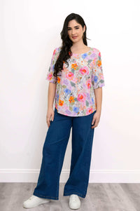 Woman standing in floral blouse and jeans, relaxed fit, front view