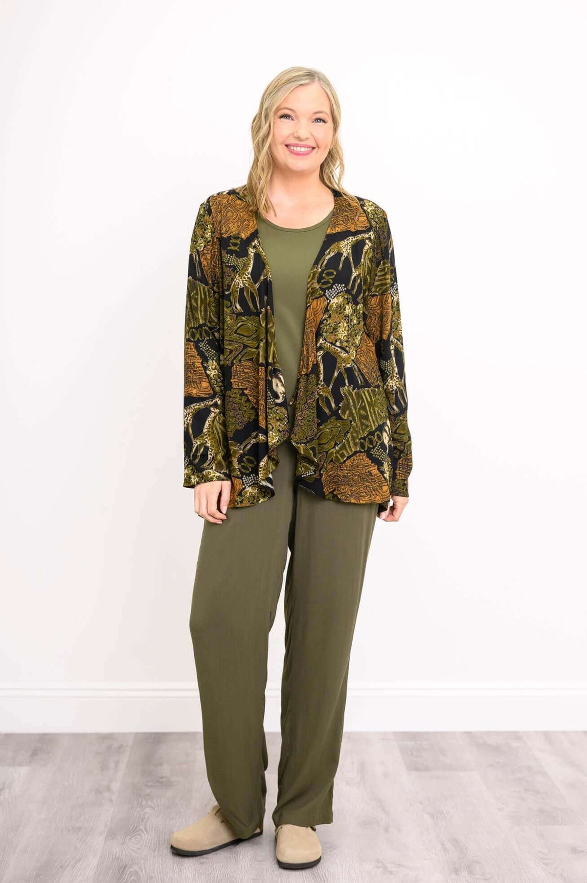 Woman standing in the Toucan Jacket, full length, in animal print and green pants