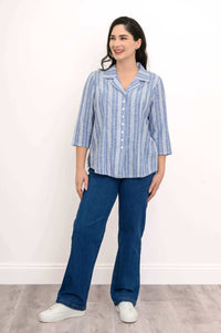 Full view of a woman in a blue and white striped shirt and blue jeans, standing on a wooden floor