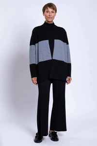 Full body view of woman in two-tone black and grey sweater and black trousers