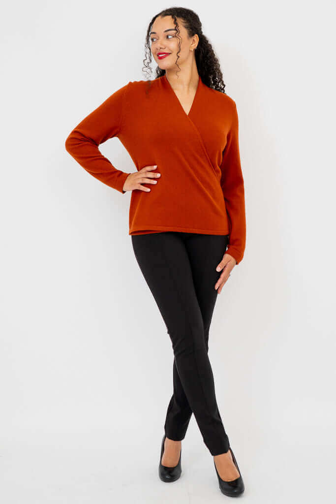 Full body view of model in rust V-neck sweater and black pants