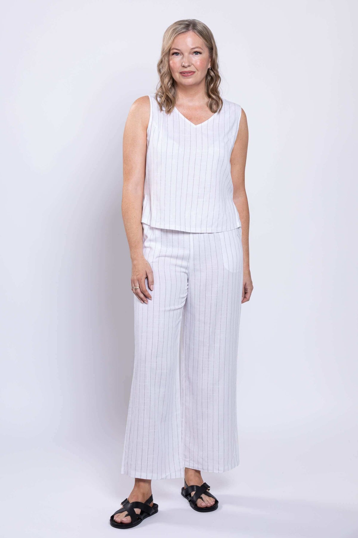 Full body view of model in white striped sleeveless tank and matching pants