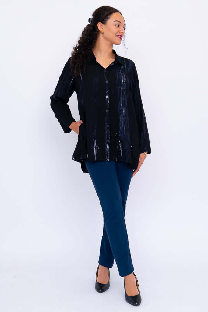 Full body view of model in black flowy tunic top paired with blue pants and black heels
