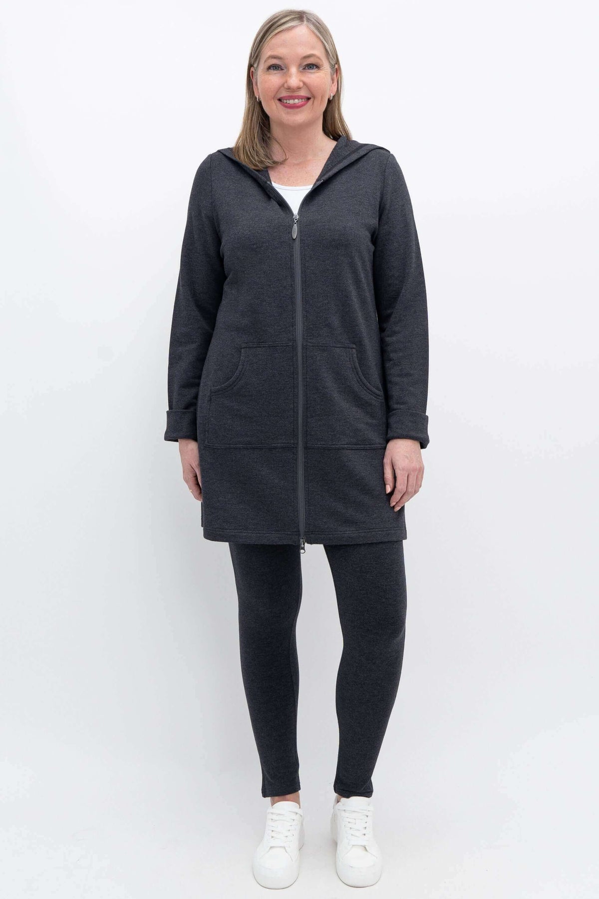 Full body view of woman in dark charcoal hooded jacket and matching leggings