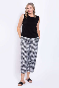 Woman modeling black tank and checkered pants, full body view