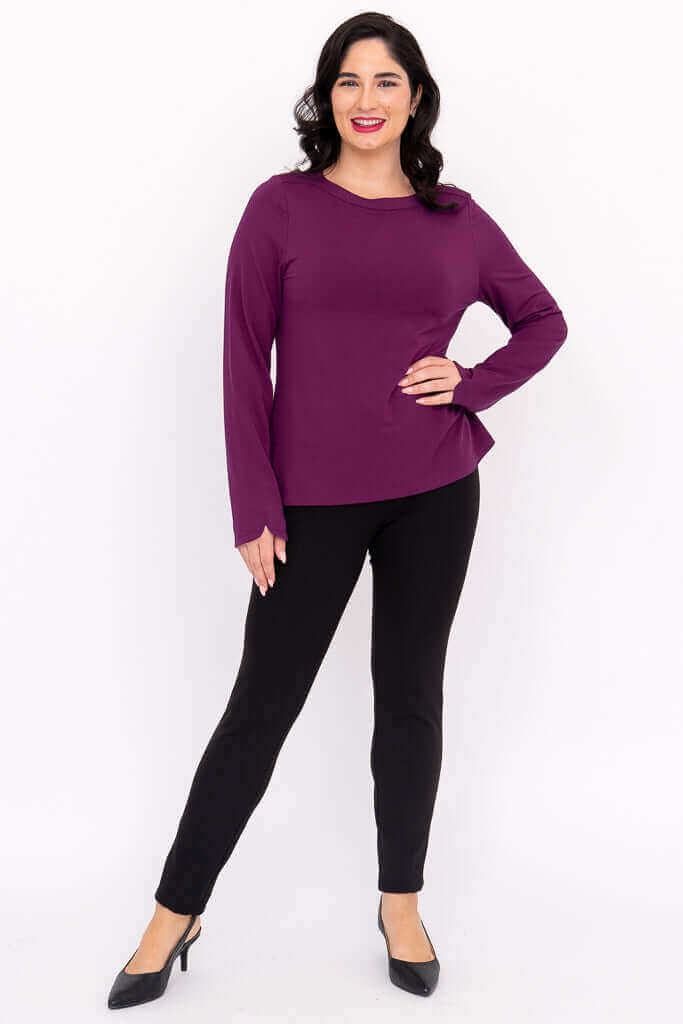 Full body view of a woman in a purple boat neck top and black pants