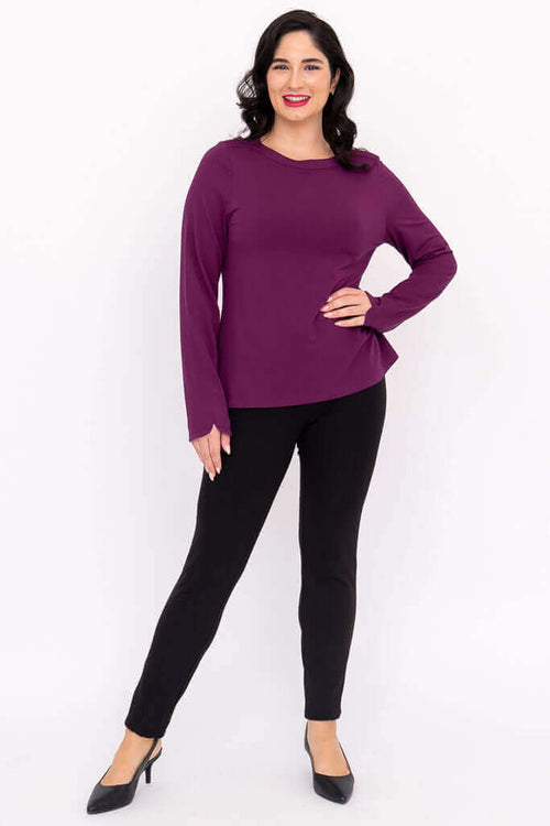 Full body view of a woman in a purple boat neck top and black pants