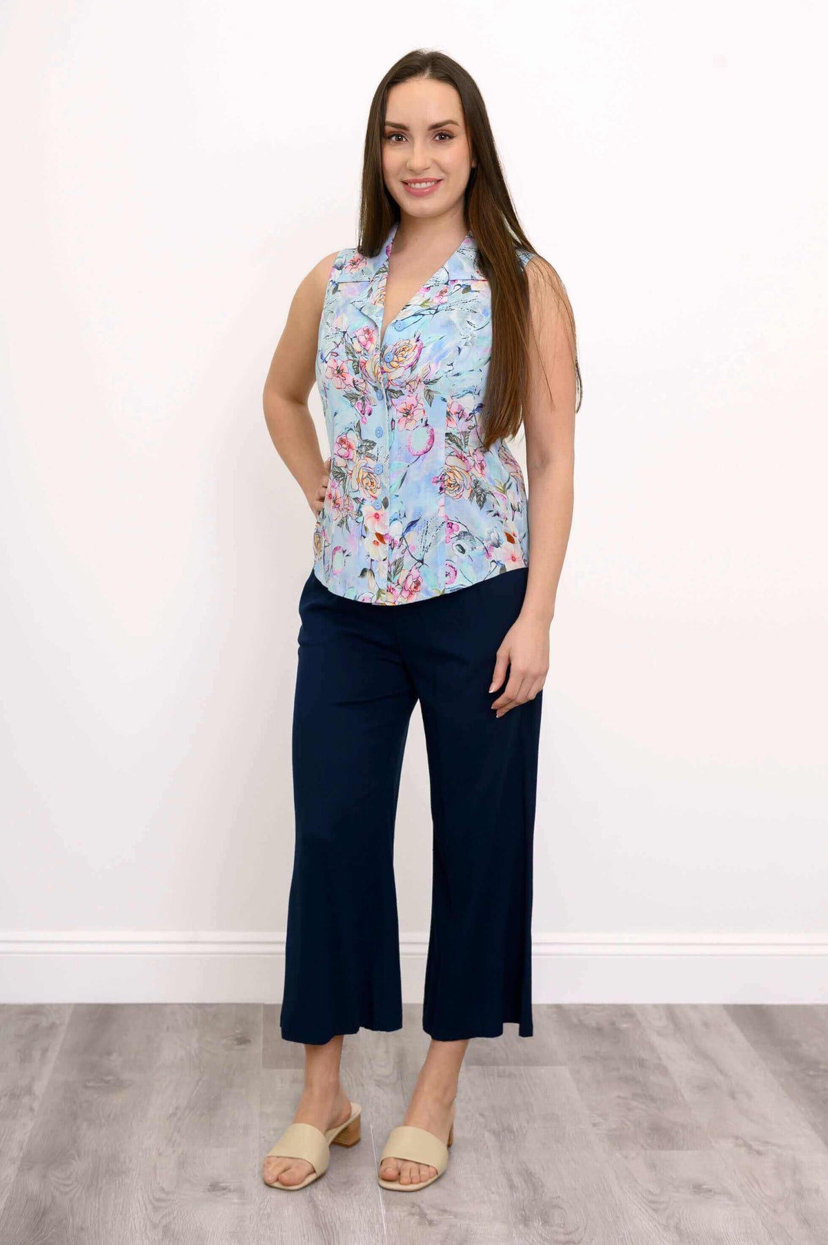 Woman showing full outfit with sleeveless floral shirt and navy pants, front view