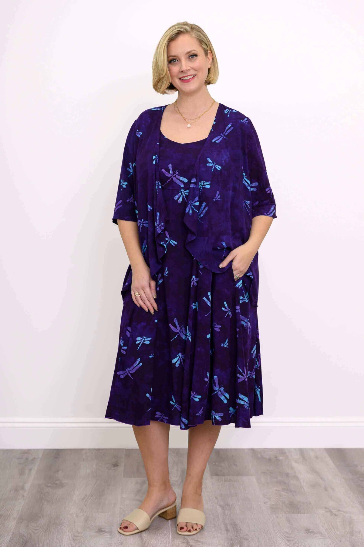 Woman in a purple dragonfly print jacket and matching dress, posing front view