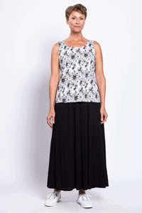 Full-body view of a woman in a black and white floral tank top paired with a long black skirt