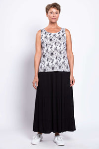 Full body view of woman in black and white floral tank top with black maxi skirt