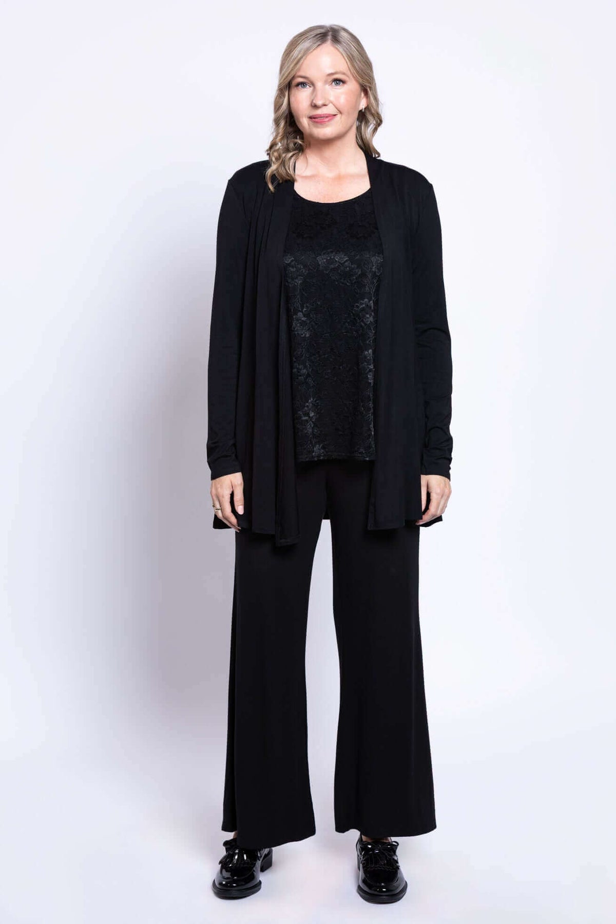 Full body front view of woman in black lace tank top, pants, and matching open cardigan