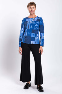 Full body view of woman in blue patchwork top and black pants