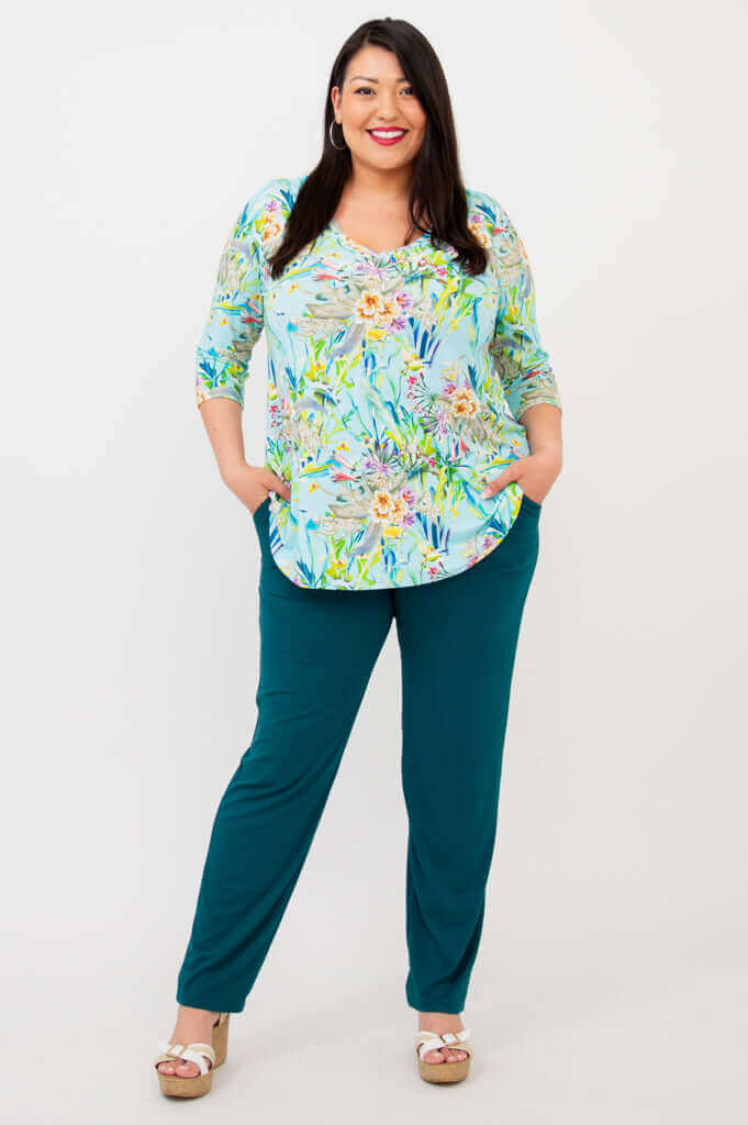 Full-length view of woman in blue floral V-neck top and teal pants