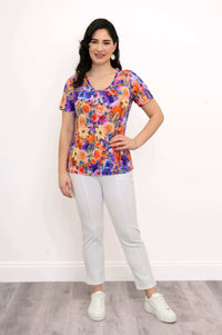 Woman in a vibrant floral bamboo top and white pants, full outfit