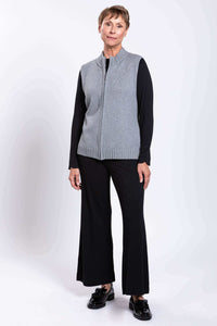Full body view of a woman in a gray zip-up cotton vest, black pants, and black shoes