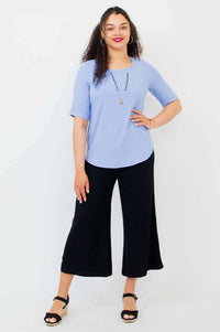 Full body shot of model in light blue blouse and black wide-leg pants