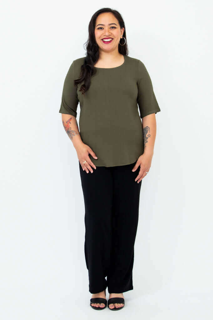 Full body view of woman wearing olive green blouse and black pants