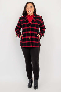 Full body view of a woman in a red and black plaid blazer and black pants