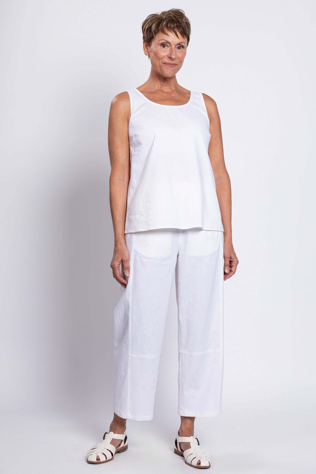 Woman standing in a white sleeveless tank and matching pants, full outfit