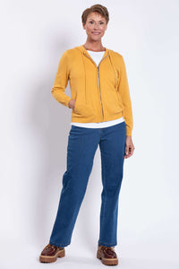 Full length view of a woman wearing a mustard yellow zip hoodie paired with dark blue denim jeans