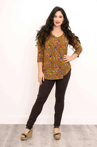 Full body view of woman in marigold floral V-neck top and dark pants