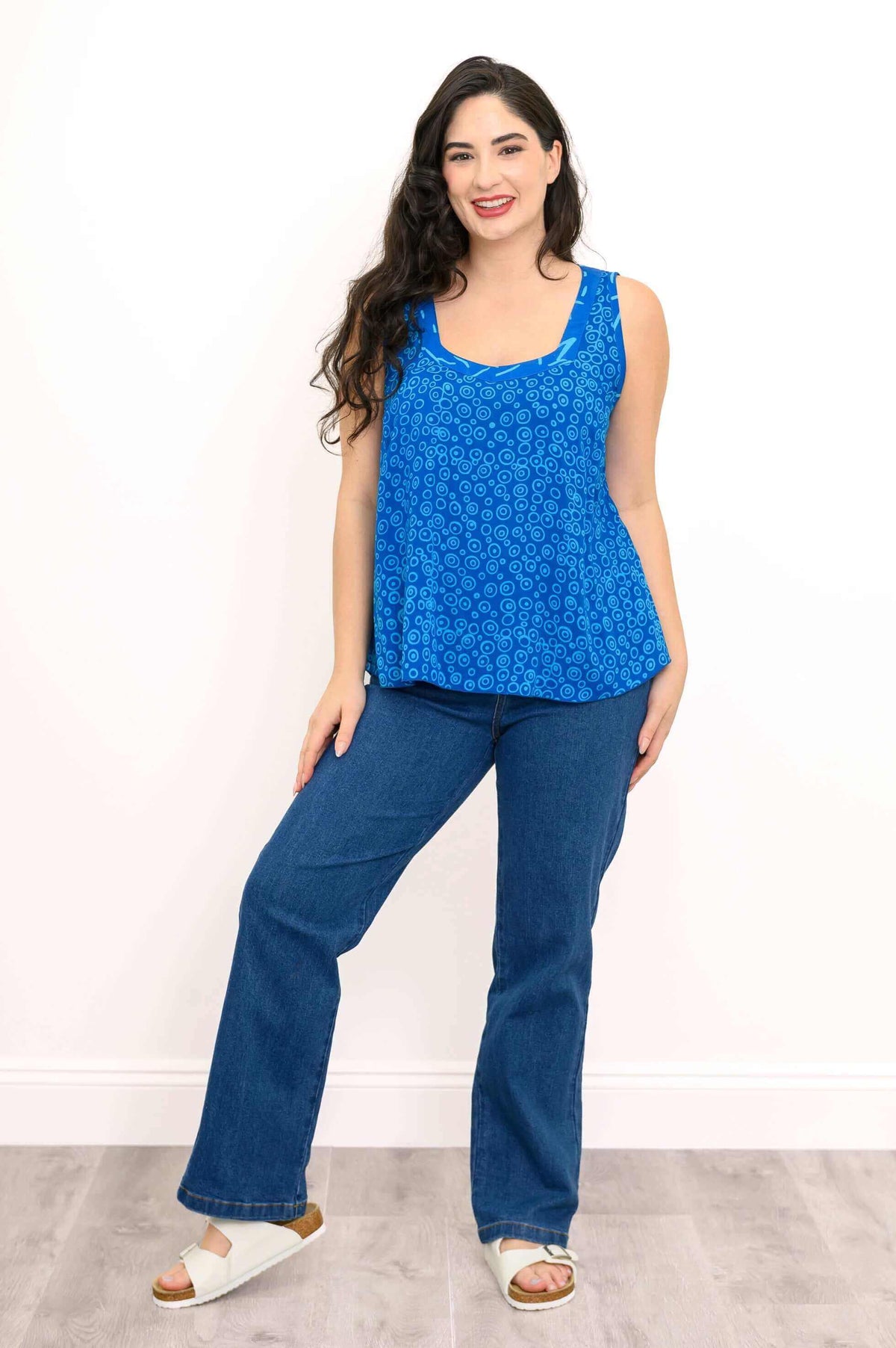 Full body view of model in blue batik sleeveless top paired with jeans