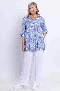 Woman standing in full view wearing blue paisley tunic and white wide-leg pants