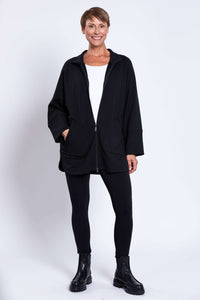 Woman in full view wearing black zip-up jacket, black leggings, and boots