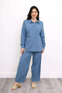 Full view of woman standing in sky blue shirt and wide-leg pants